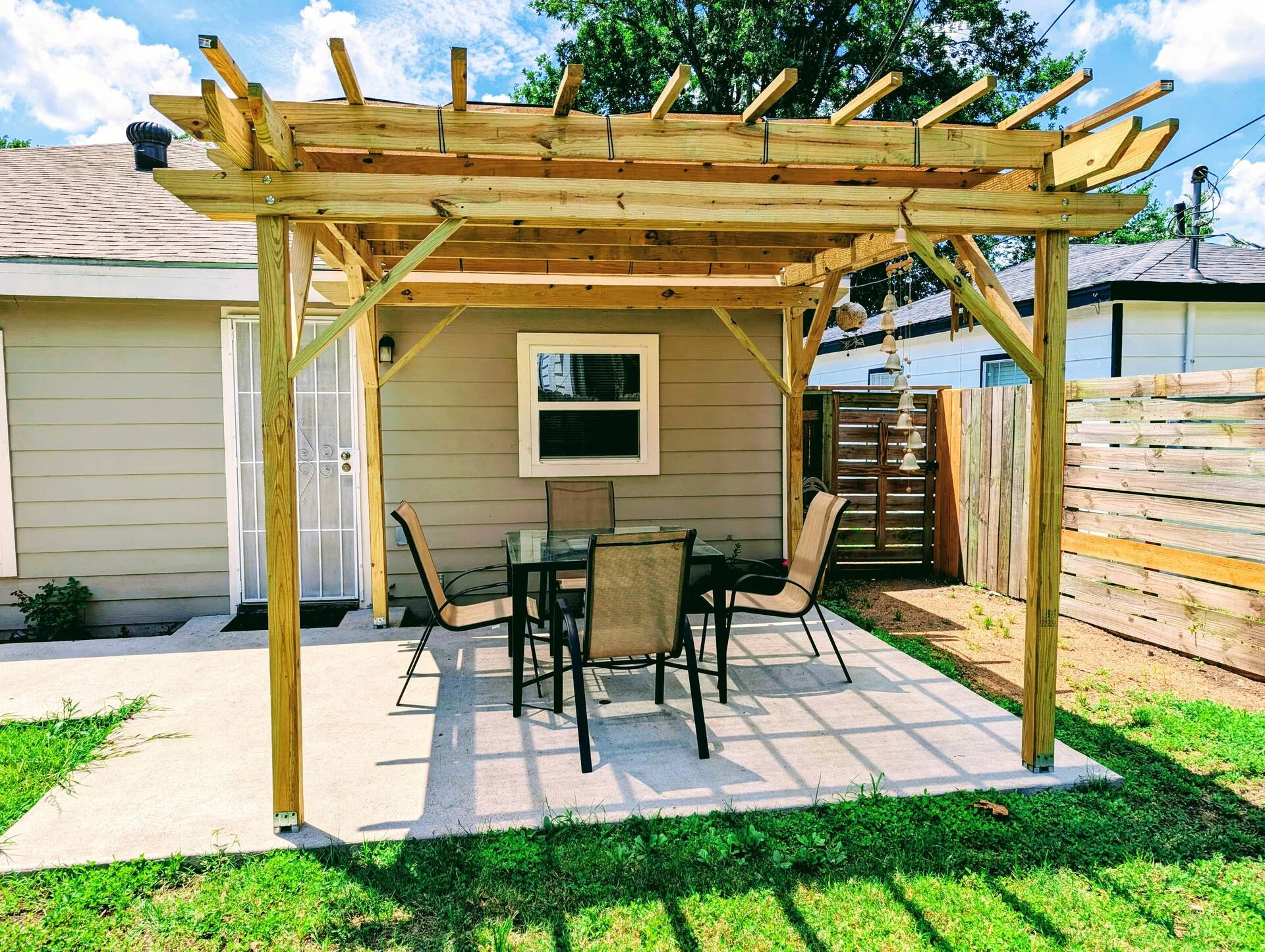 Pérgola de madera con mesa y sillas en el jardín